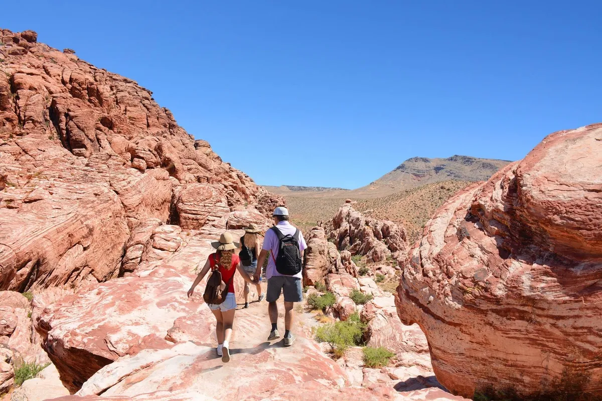 This exterior image captures striking red rock formations under a clear blue sky, with hikers in the foreground exploring the natural landscape. The sense of adventure and discovery is palpable, inviting families to imagine outdoor excursions and memorable explorations.