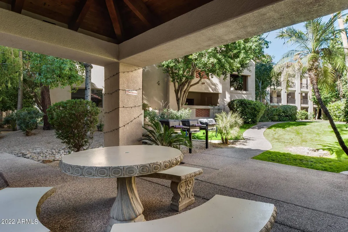 A cozy outdoor seating area nestled among lush greenery, featuring a decorative table and comfortable chairs. The space invites guests to relax with morning coffee or hold informal meetings in a peaceful garden setting.