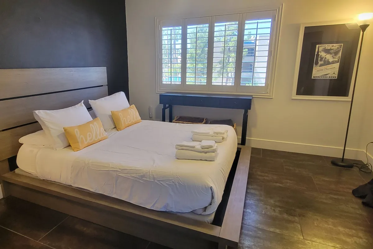 A cozy and inviting guest bedroom with a comfortable full-size bed adorned with decorative pillows, a window with shutters allowing for abundant sunlight, and framed artwork adding a personalized touch. The peaceful atmosphere is perfect for a restorative escape.
